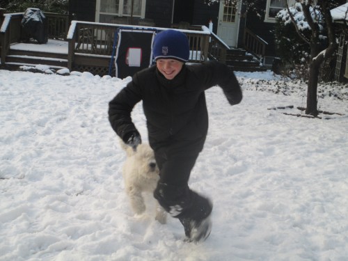 Puppy and boy play in snow on carpoolcandy.com